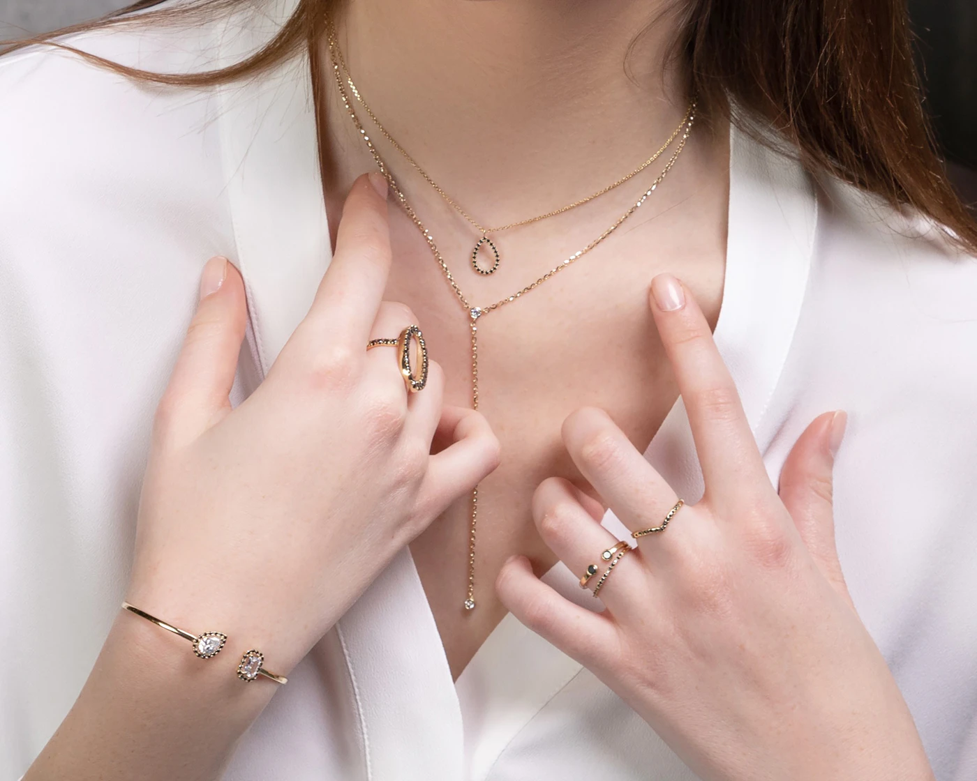 Layered fine gold necklaces, rings and a bracelet worn together