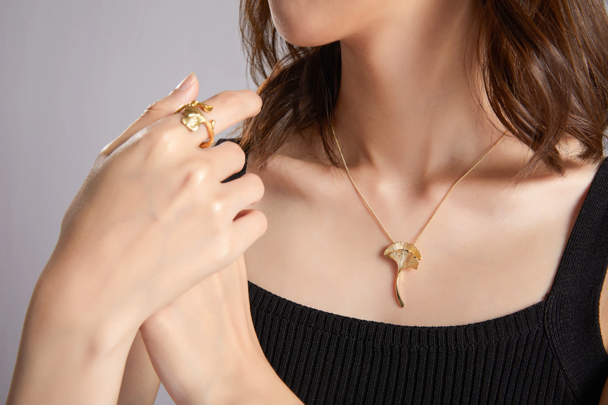 A woman in black wearing a fine gold pendant necklace