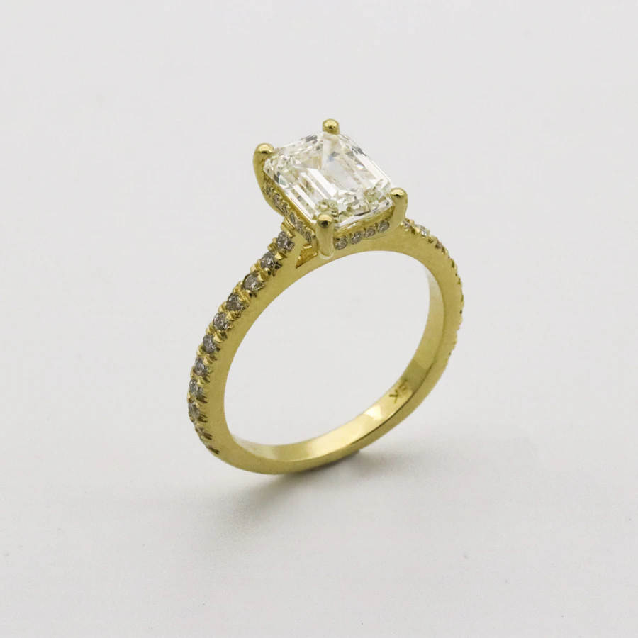 Emerald-cut solitaire ring in yellow gold with a pavé band